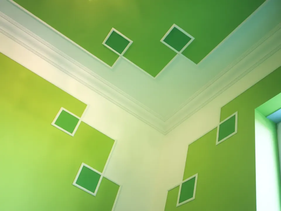 Room corner with plaster coving and diamond mouldings on green walls