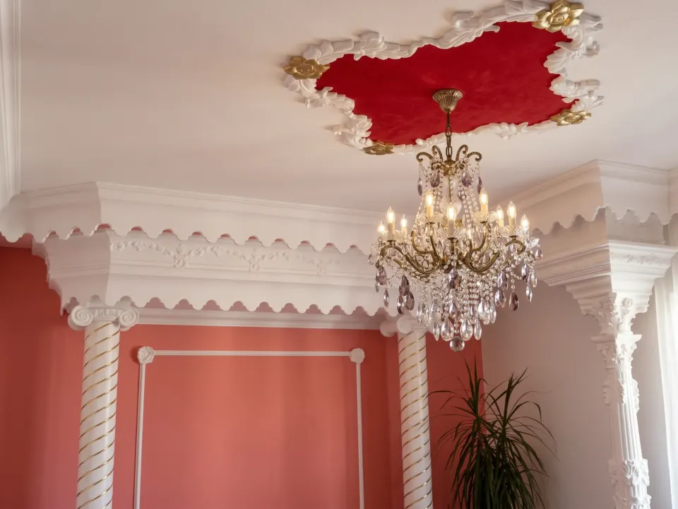Ceiling with a red rosette and a crystal chandelier, plaster coving and columns